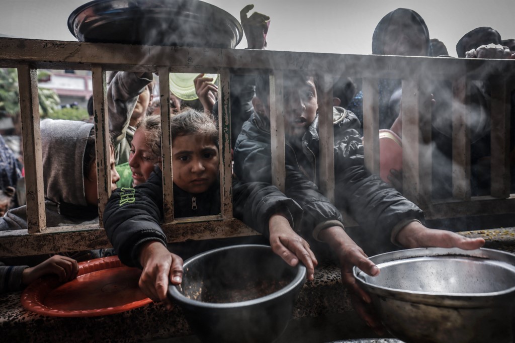 Displaced Palestinian children wait to receive food in Rafah, Gaza Strip, 19 February 2024 (Mohammed Abed/AFP)