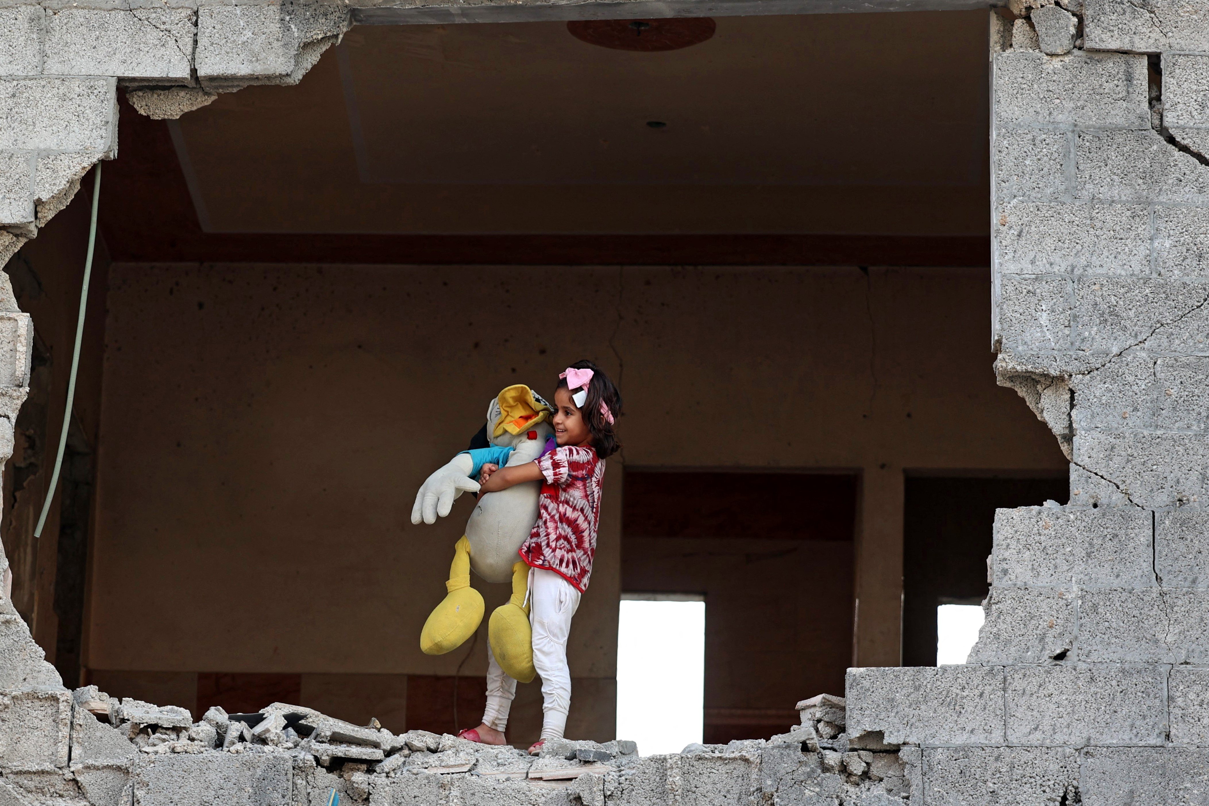 Une fillette palestinienne tient sa peluche à l’intérieur de sa maison fortement endommagée lors de la dernière offensive israélienne contre Gaza, le 5 août 2021 (AFP)