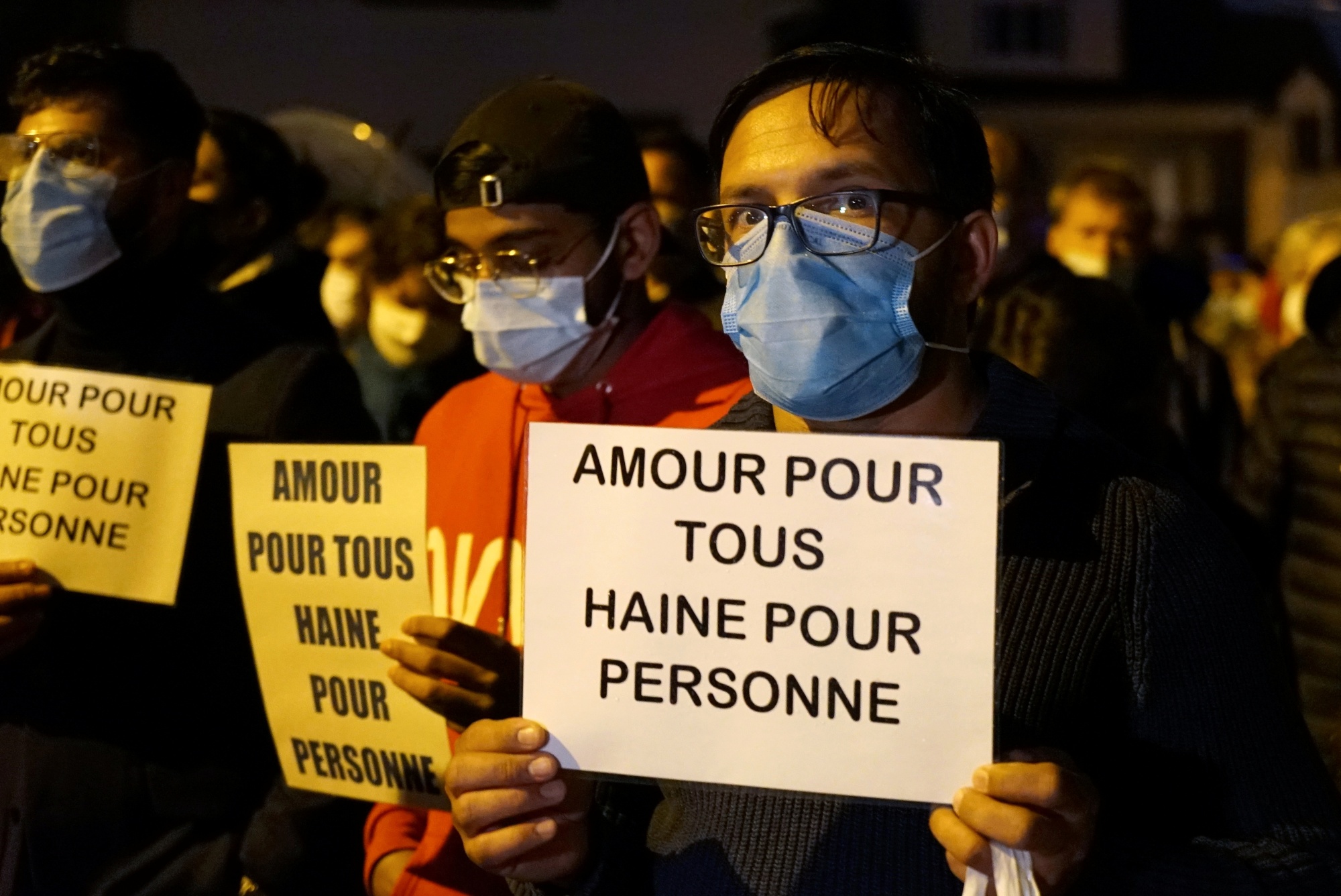 People attend a silent march to pay tribute to Samuel Paty in Conflans-Sainte-Honorine, France, on 20 October 2020. The slogan reads "Love for all, hatred for no-one" (Reuters)