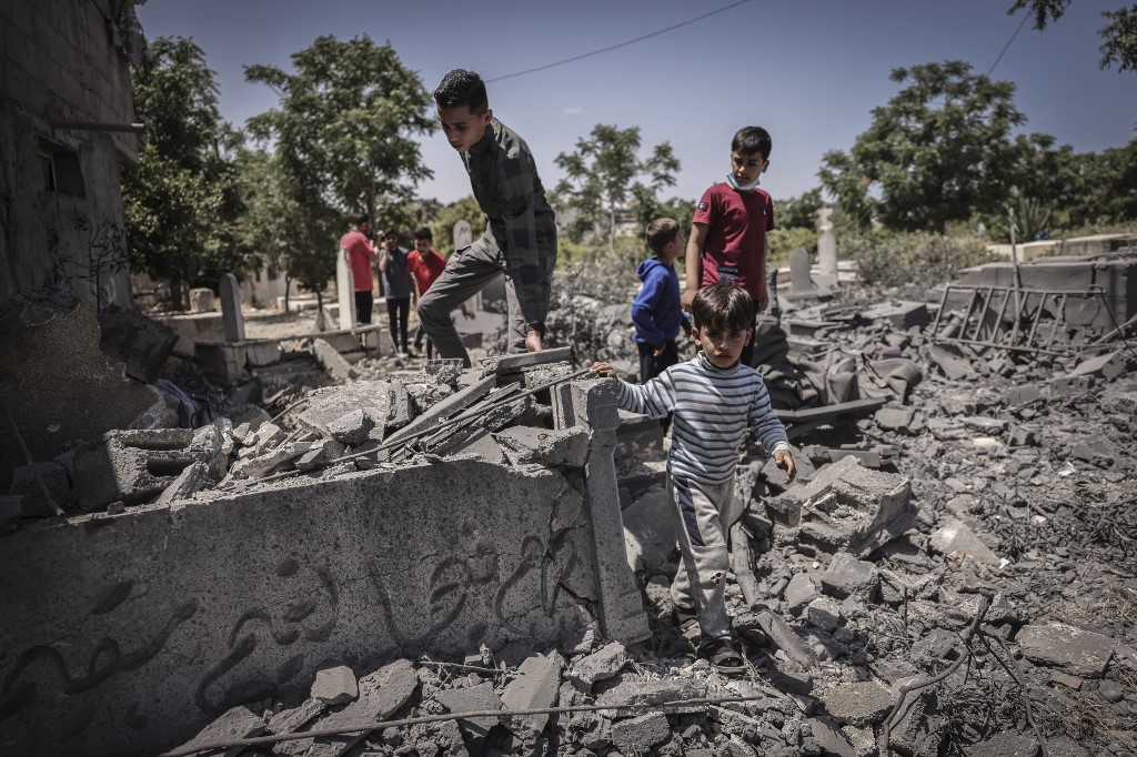 People inspect the damage in a graveyard hit by an Israeli air strike in Beit Lahia in the northern Gaza Strip, on May 13, 2023 (Mohammed Abed / AFP)