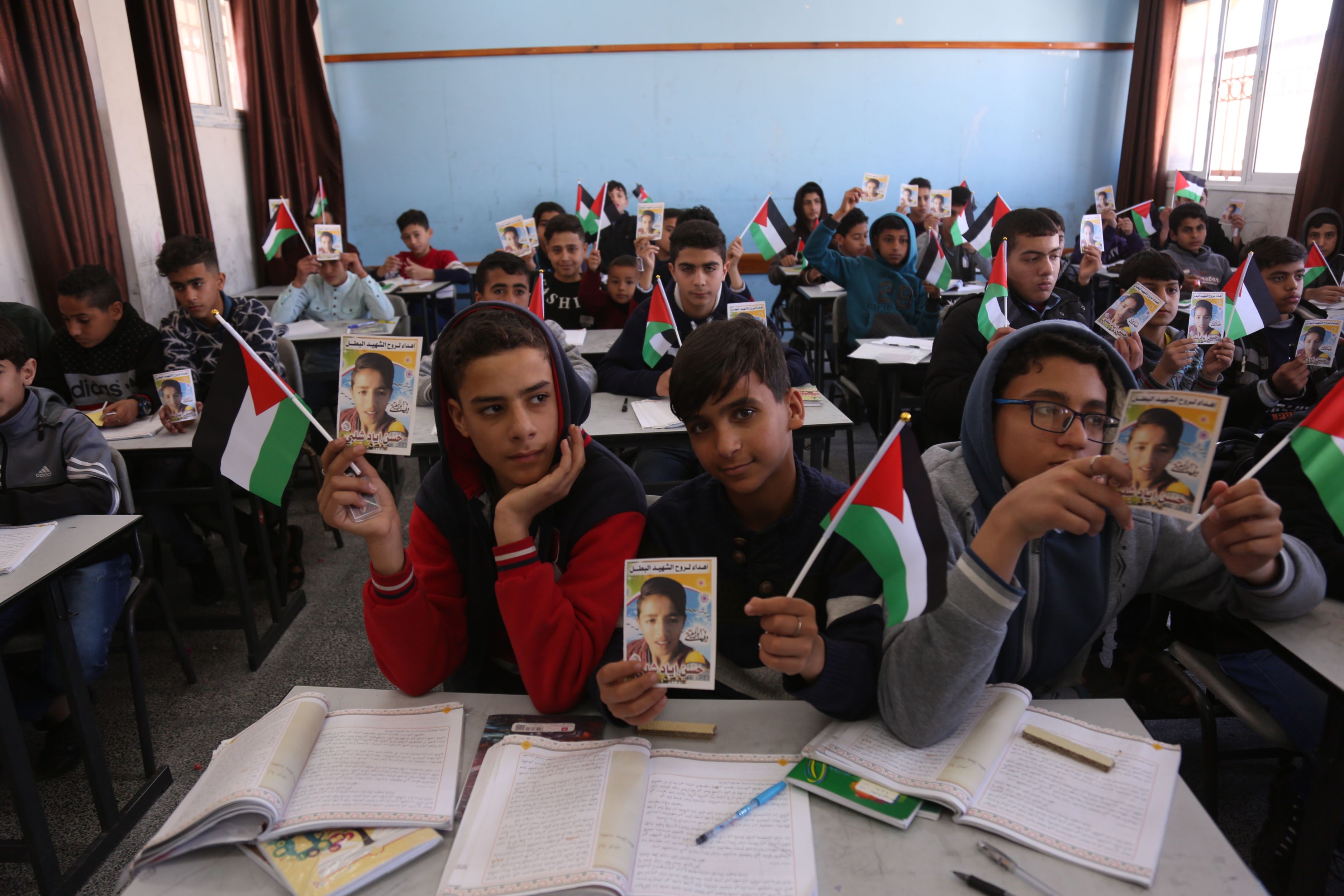 Hassan's classmates hold up photos of the slain boy (MEE/Samar Abu Elouf)