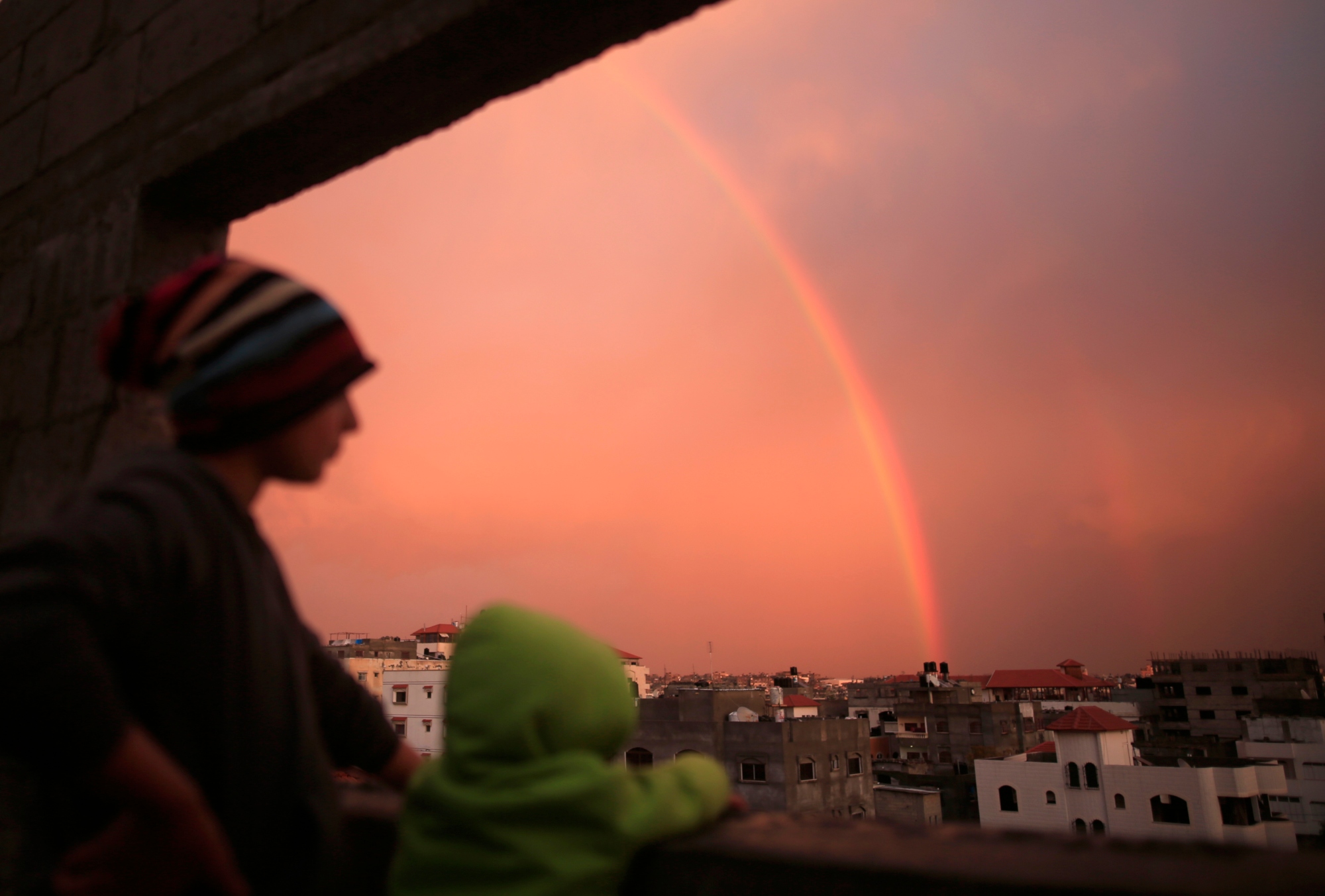 Caption: Palestinian children look at a rainbow appearing over Gaza City on 15 February 2017 (AFP)
