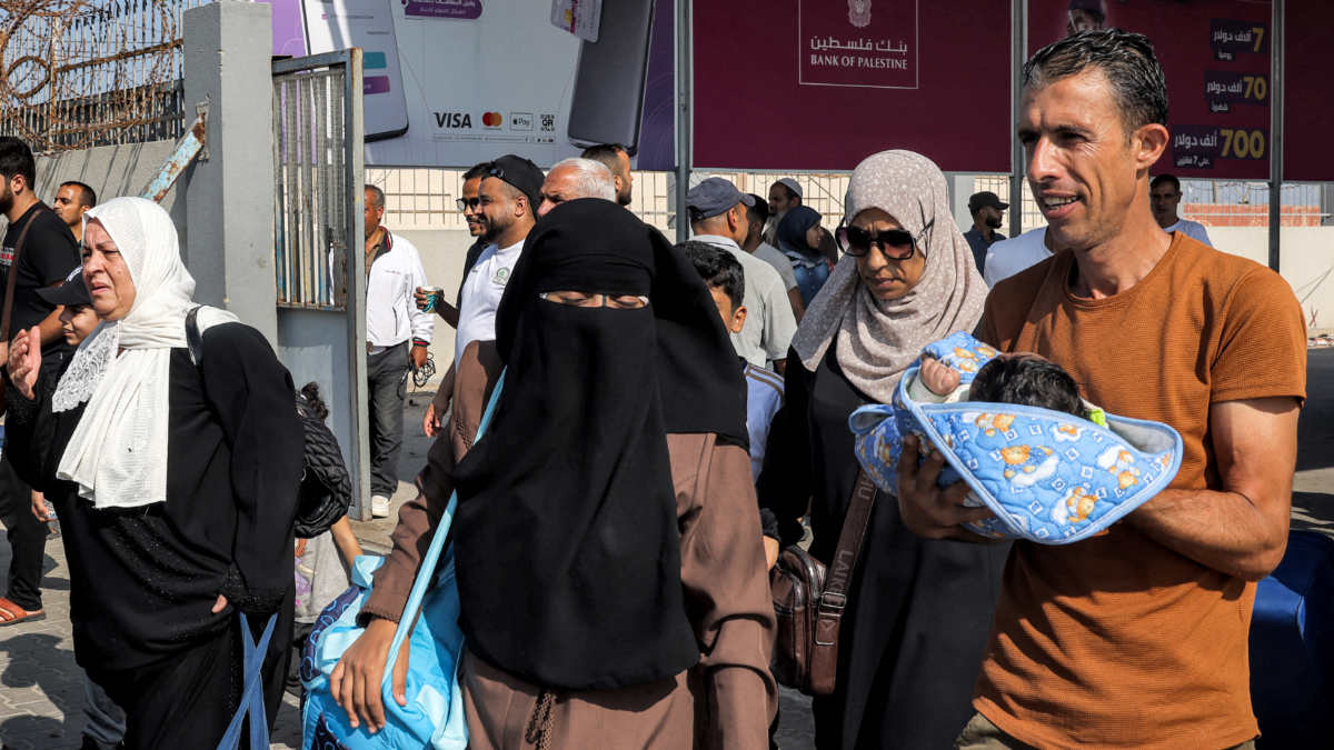 Des personnes pénètrent dans le poste-frontière de Rafah dans le sud de la bande de Gaza avant de passer en Égypte, le 1er novembre 2023 (AFP)
