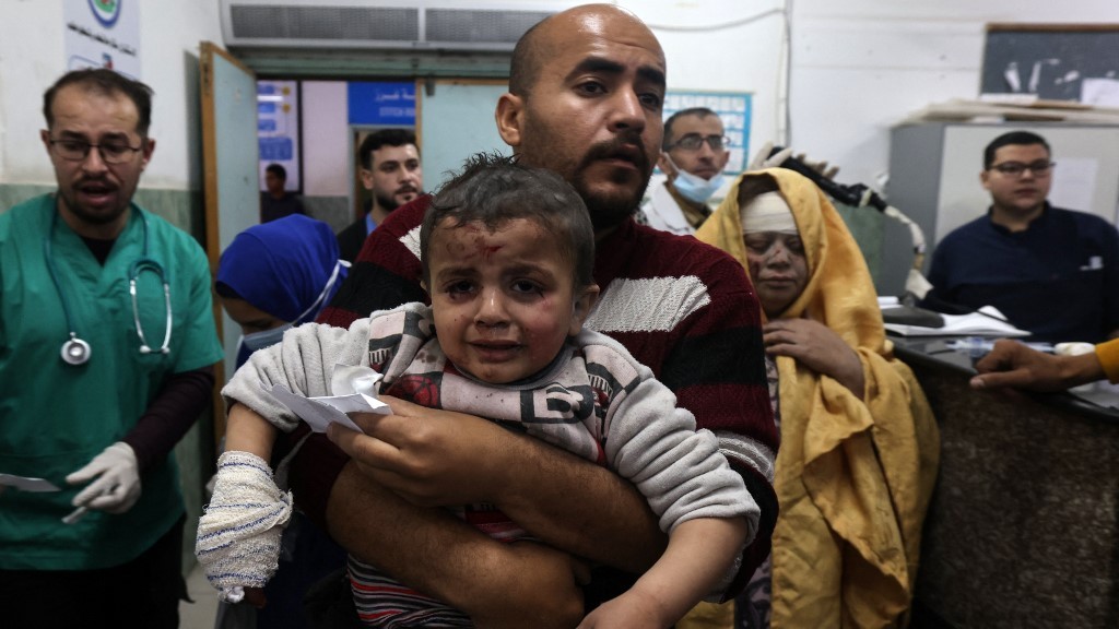 A man carries a child injured in Israeli bombardment in the al-Najjar hospital in Rafah in March 2024 (AFP/Mohammed Abed)