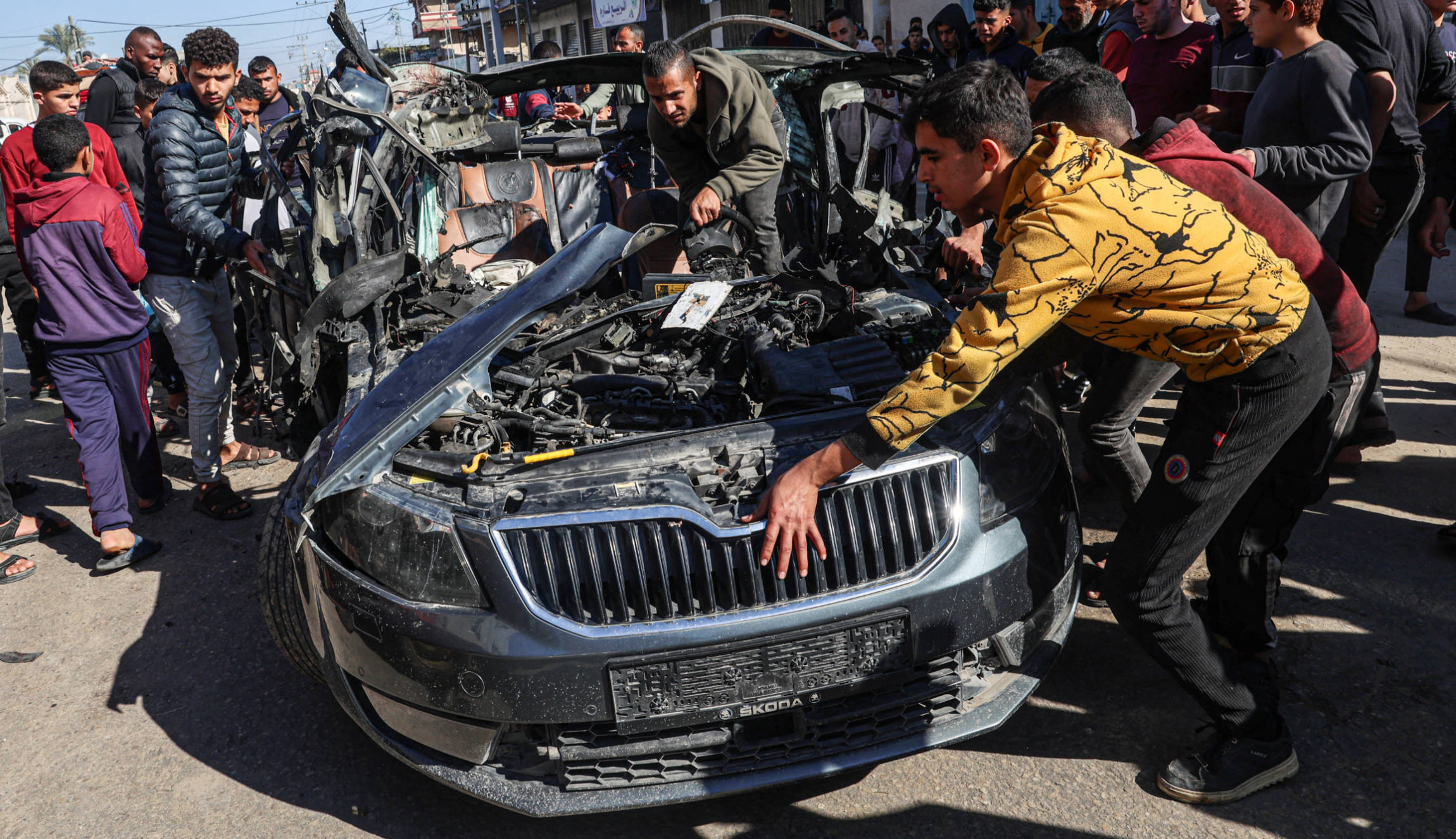 People check the car in which journalists Hamza Wael Dahdouh and Mustafa Thuria were killed in Israeli strike in Rafah in the Gaza Strip on 7 January 2024 (AFP)