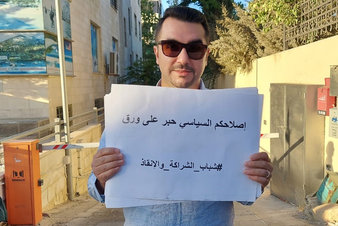 Protester holds up a sign reading 'Your political reform is just dead letters on a paper' outside the Independent Election Commission in Amman (MEE/Mohammad Ersan)