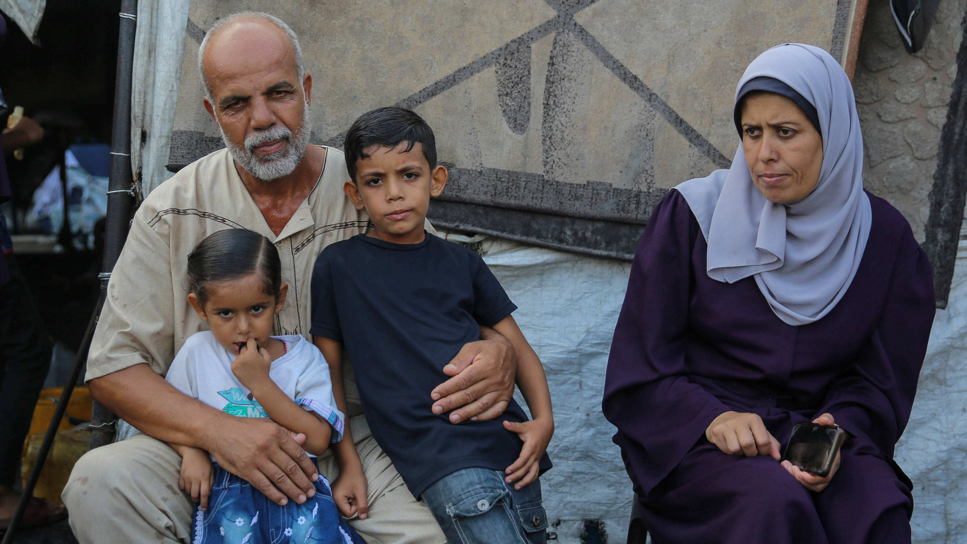 Seven-year-old Ibrahim Mubayyad poses for a photo with his parents and sister in an Unrwa school in Deir al-Balah, Gaza Strip (Mohammed al-Hajjar/MEE)