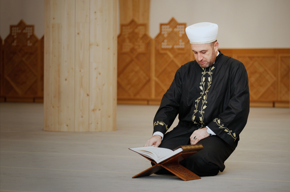 Imam Ali Tos demonstrates the pose a muezzin takes when reciting the adhan (Cambridge Central Mosque)