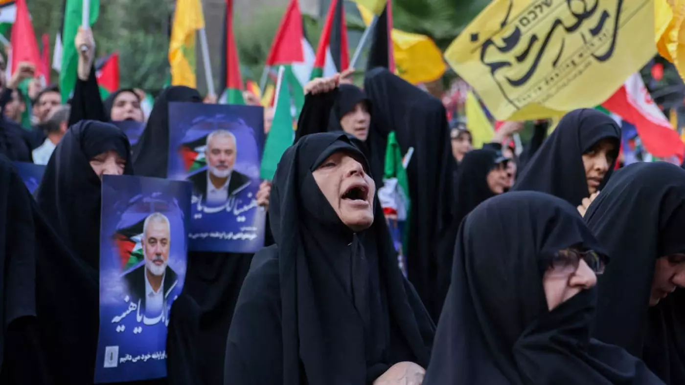 Iranians wave Palestinian flags and hold portraits of slain Hamas leader Ismail Haniyeh during a protest denouncing his killing, at Palestine Square in Tehran, on 31 July 2024 (AFP)