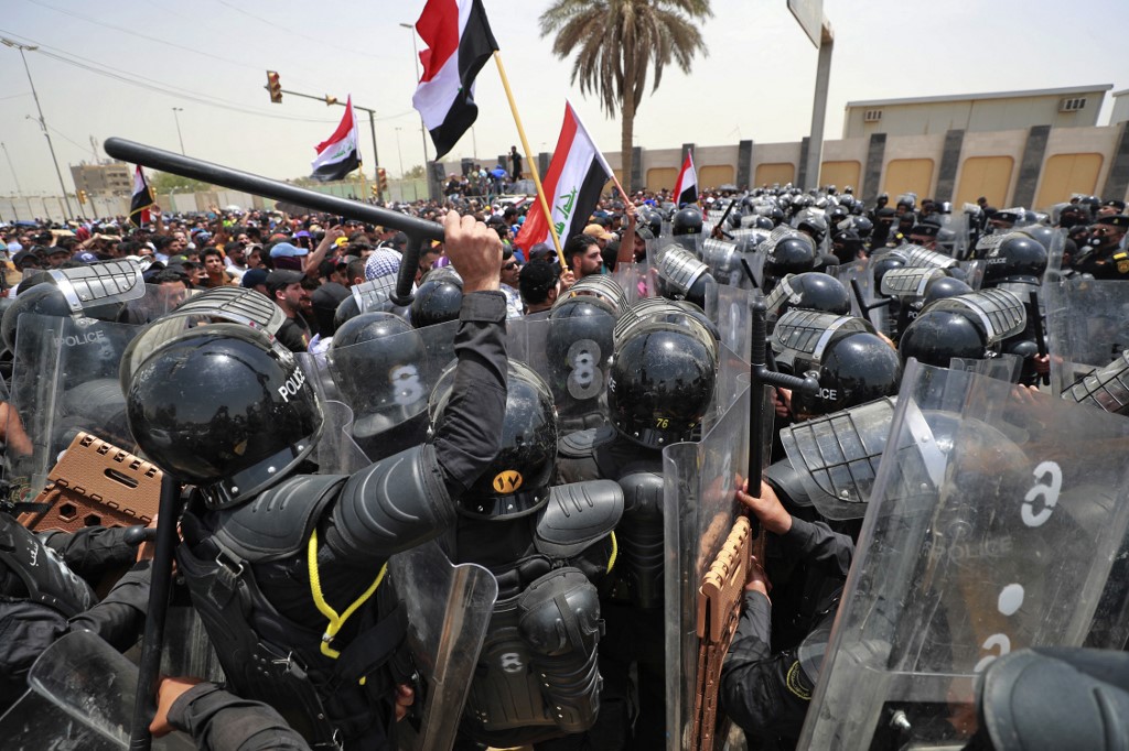 Iraqi security forces disperse protesters during a demonstration against the government’s employment policy near the parliament building in Baghdad's Green Zone, 7 June 2022 (AFP)