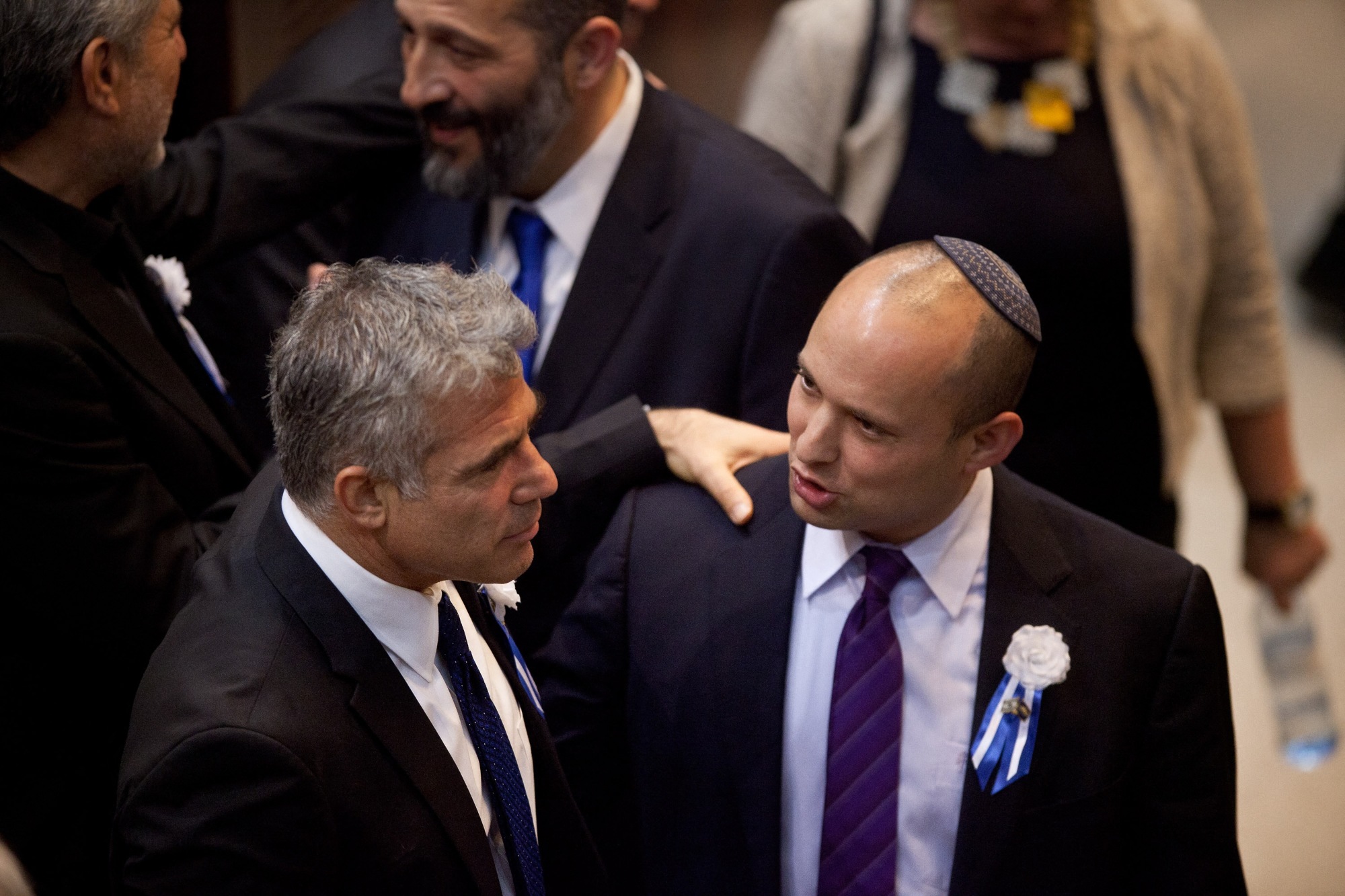 Yair Lapid, left, embraces Naftali Bennett during a reception marking the opening of the19th Knesset on 5 February 2013 in Jerusalem (AFP)