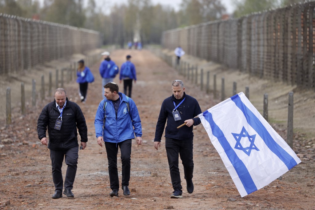 Participants walk with the national flag of Israel past fences at the site of the former Auschwitz-Birkenau camp during commemorations to honour the victims of the Holocaust, near the village of Brzezinka near Oswiecim, Poland on April 28, 2022.