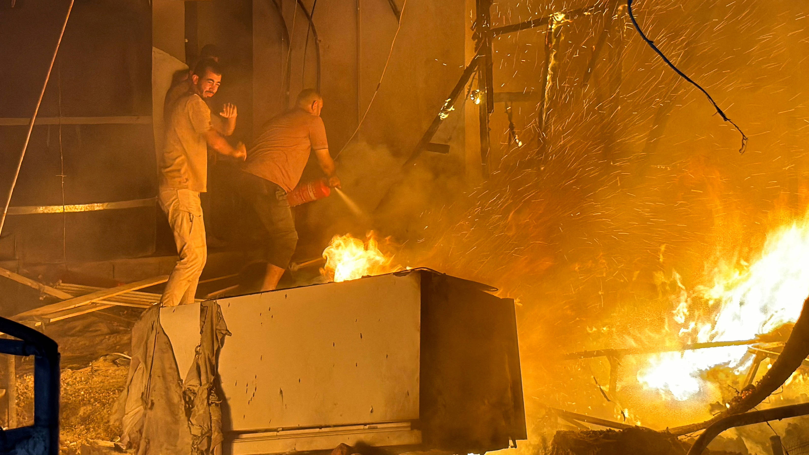 Palestinians try to extinguish a fire at the site of an Israeli air strike on a tent camp for displaced people in Deir al-Balah, central Gaza, on 4 August 2024 (Reuters)