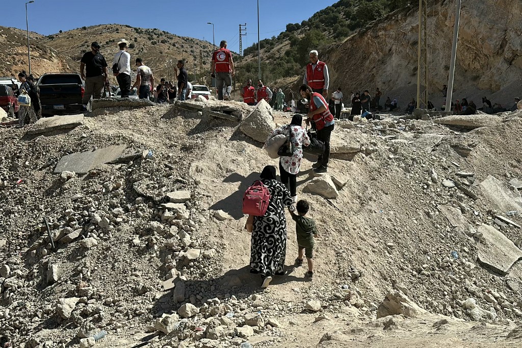 Red Crescent volunteers help people fleeing Israeli bombardment in Masnaa on the Lebanese side of the border with Syria, 15 October 2024 (Maher al-Mounes/AFP)