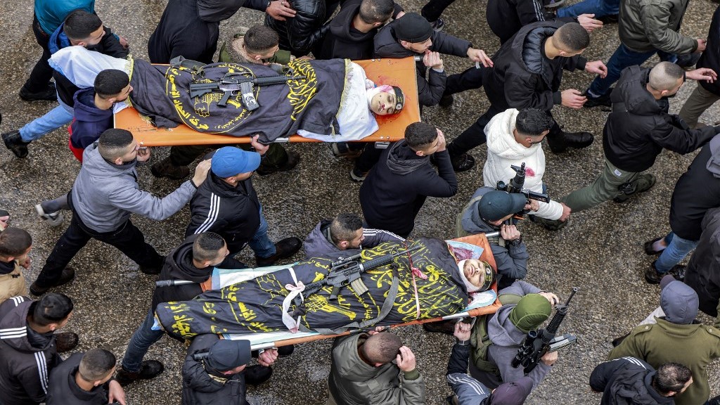 Mourners march carrying the bodies of Muhammad Ayman Ghazawi and Basel Ayman Ghazawi, two of three Palestinian men who were killed when undercover Israeli agents in January (Jaafar Ashtiyeh / AFP)