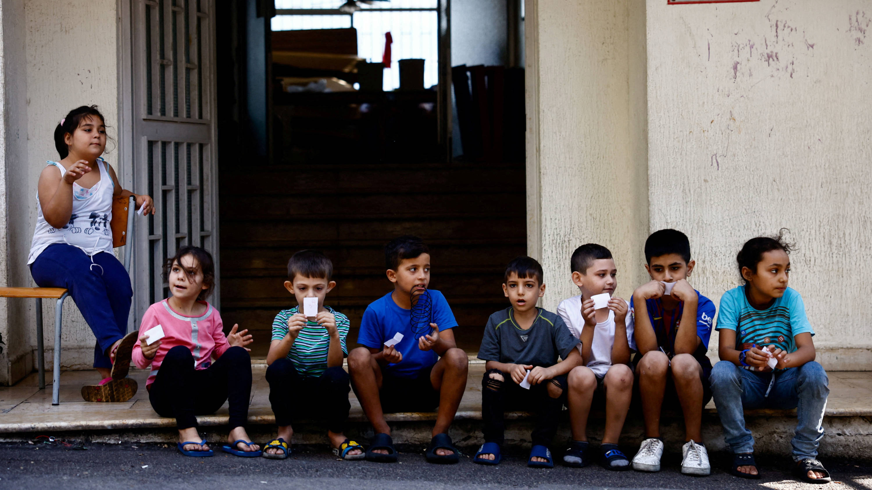 Displaced children sit on the pavement by the entrance of school turned into shelter in Baabda, Lebanon, 31 October 2024 (Reuters/Yara Nardi)