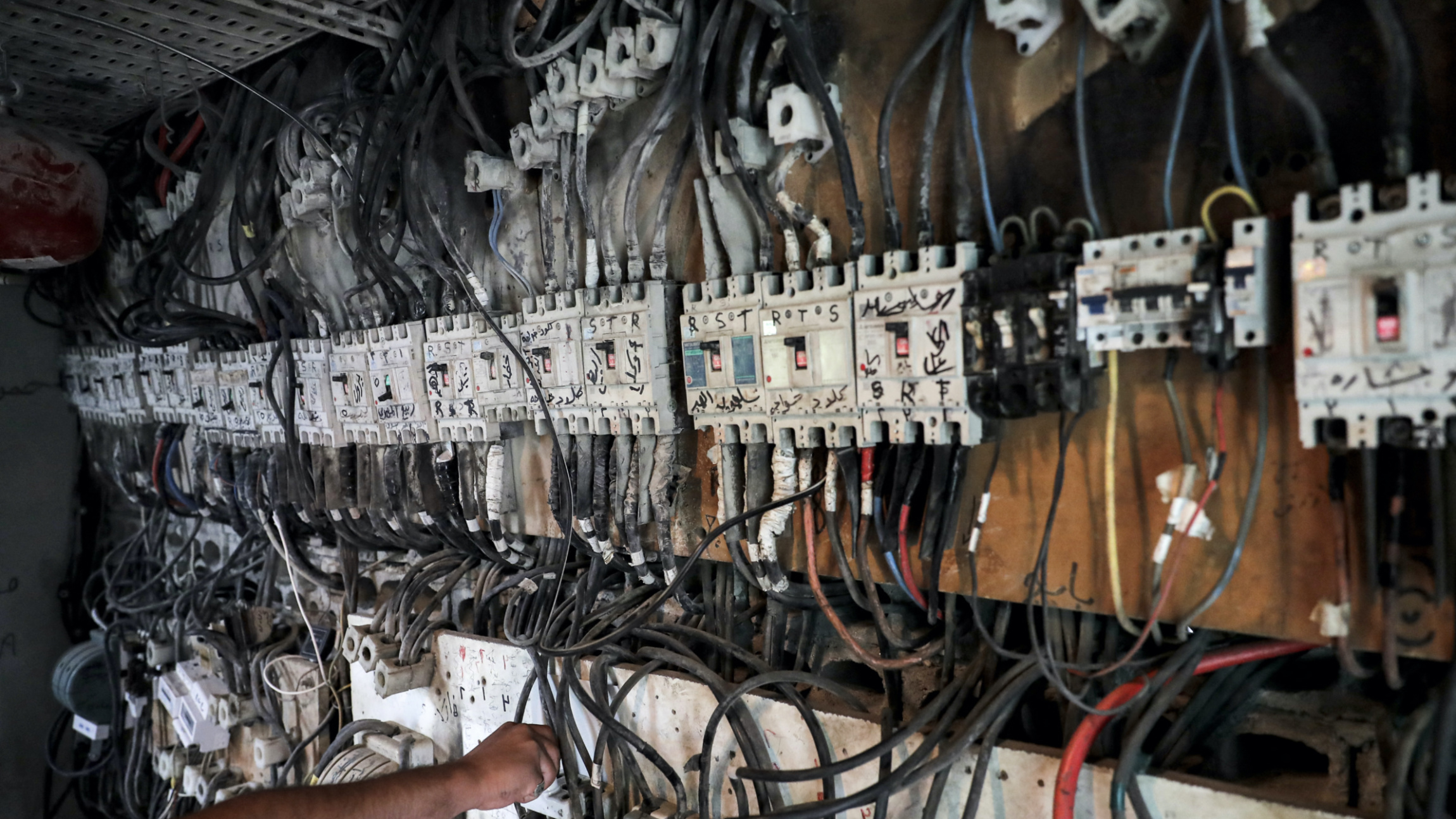 A technician controls an electric switch board connecting homes to electricity generators in a suburb of Lebanon's capital Beirut on 23 June 2021 (AFP)