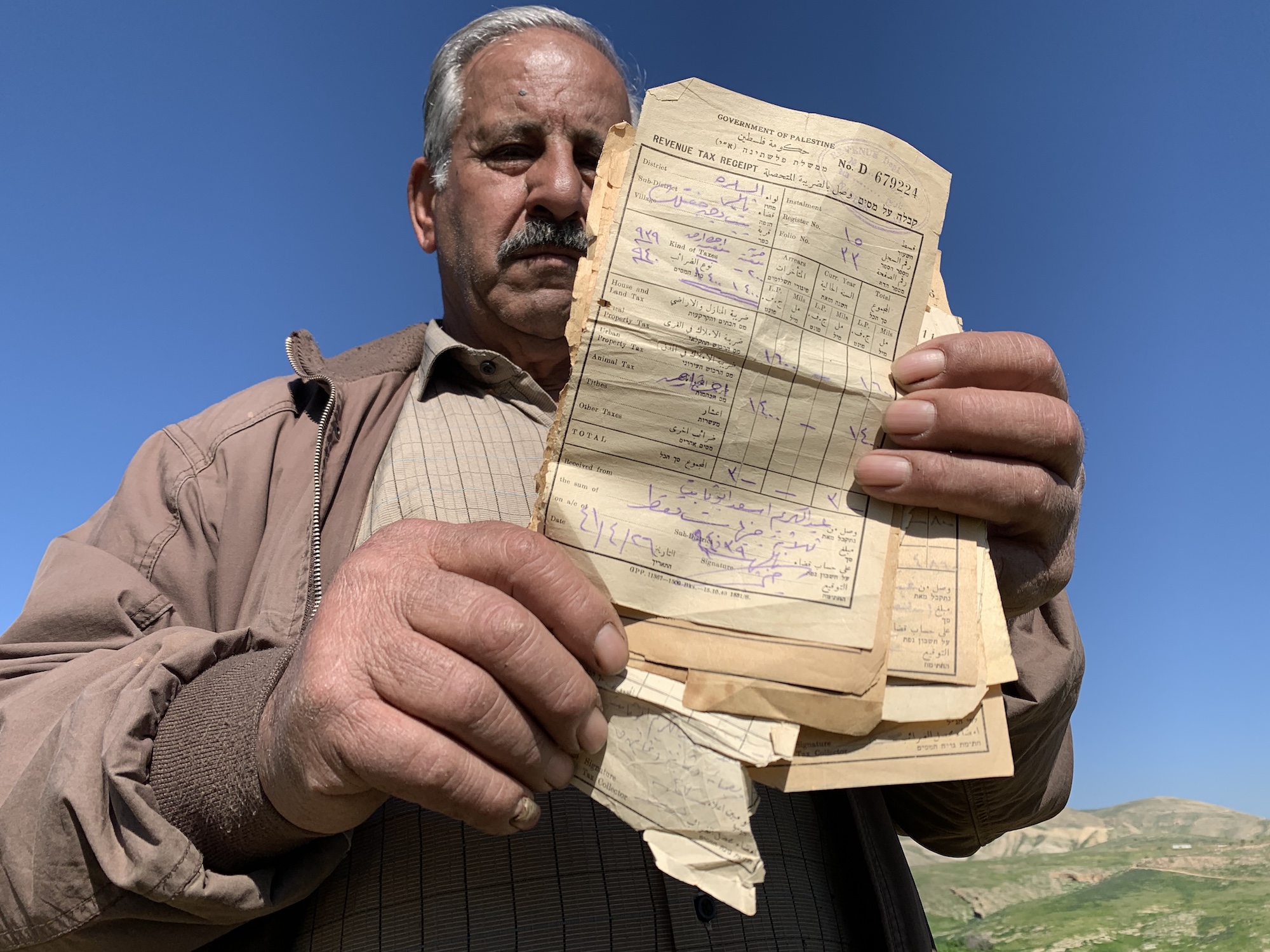 Palestinian farmer Thabet holding land ownership documents
