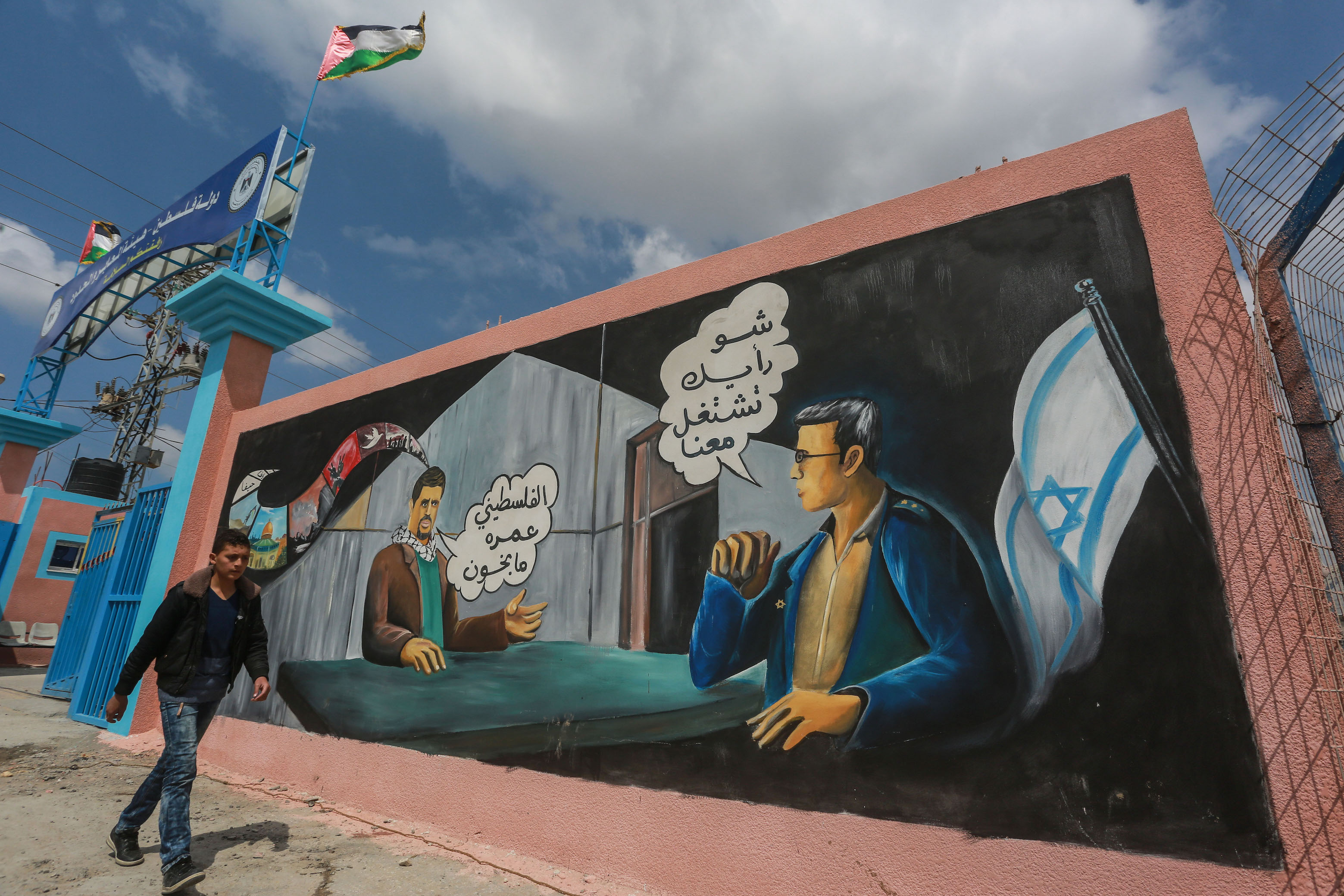 Une fresque près du poste-frontière de Beit Hanoun entre Gaza et Israël demande « Que pensez-vous de travailler pour Israël ? » suivi de la réponse « Le Palestinien n’est pas un traître » (MEE/Mohammed al-Hajjar)