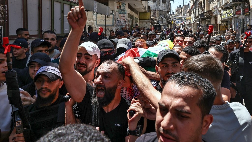 Children look on as mourners carry the body of Wael Masha, who was killed during an Israeli airstrike on the Balata refugee camp east of Nablus that killed two Palestinians (Zain Jaafar / AFP)