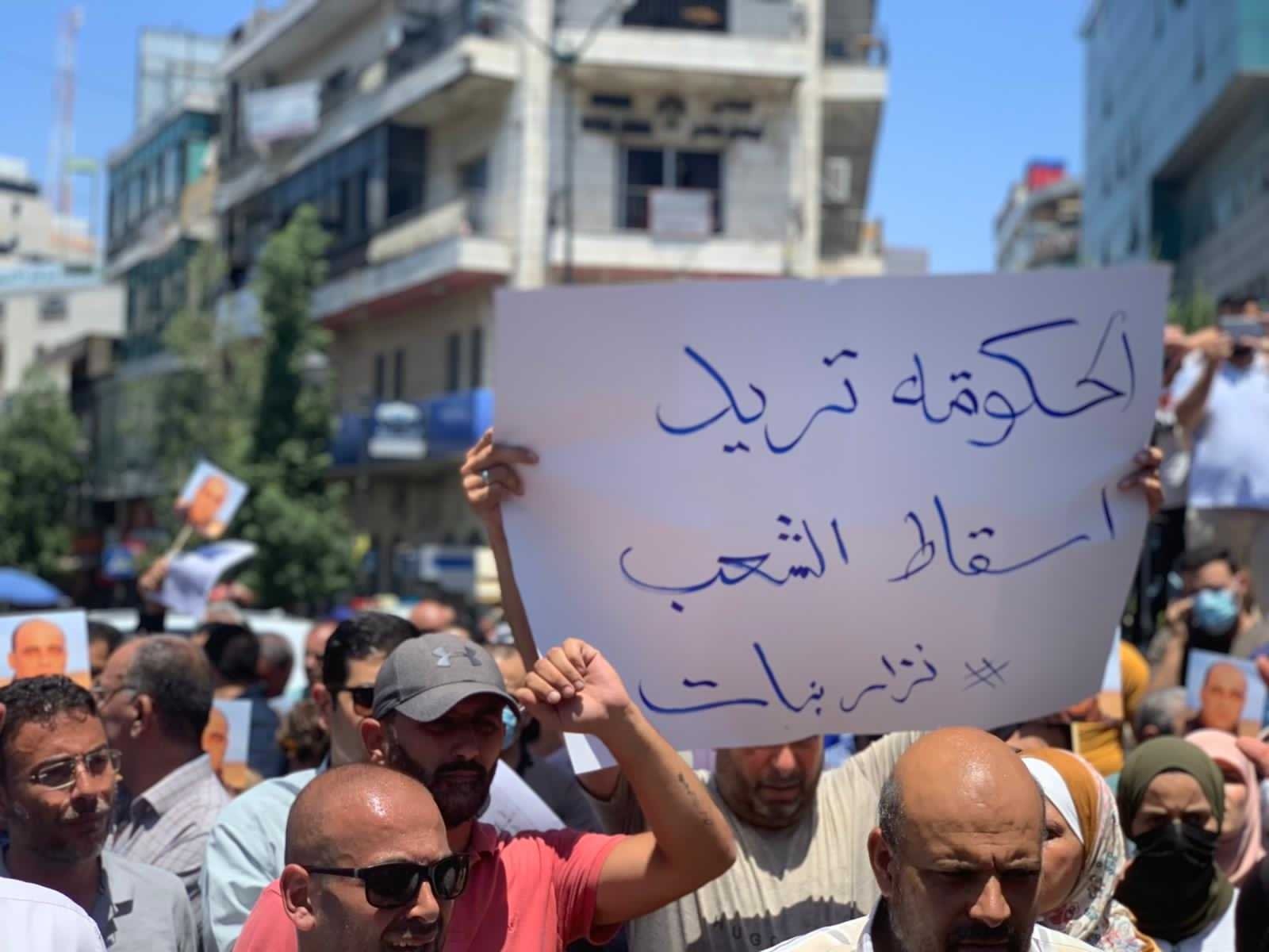 Un manifestant à Ramallah tient une pancarte sur laquelle on peut lire « Le régime veut la chute du peuple », le 24 juin 2021, après la mort de Nizar Banat (MEE/Shatha Hammad)