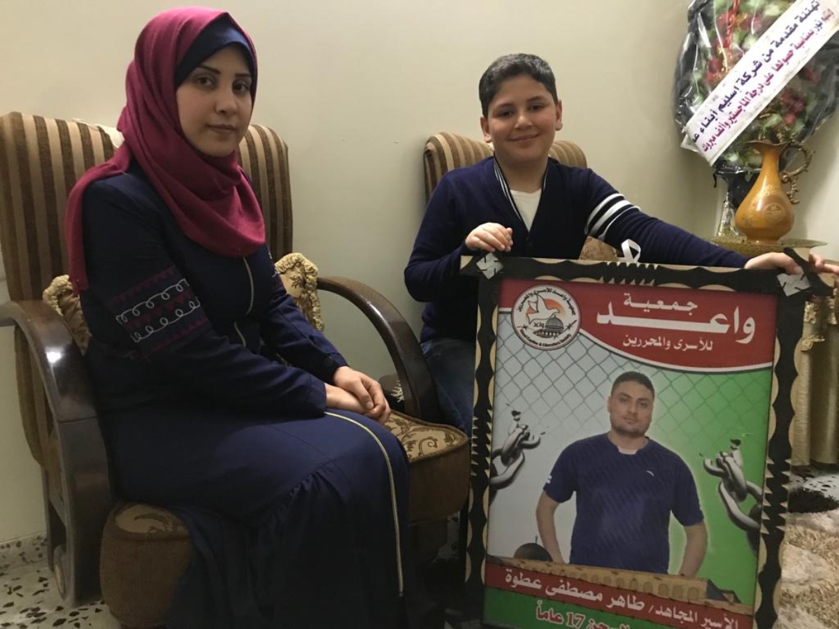 Nour and her son Mohammed pose next to a photograph of her husband Taher (MEE/Motasem Dalloul)