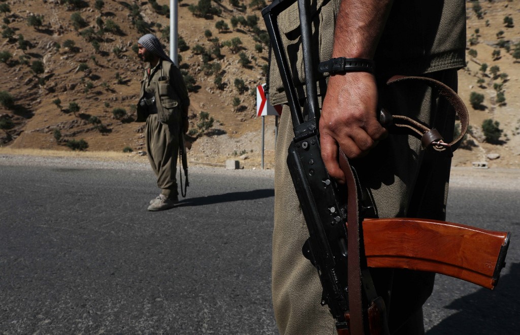 A member of the Kurdistan Workers' Party (PKK) carries an automatic rifle on a road in the Qandil Mountains, the PKK headquarters in northern Iraq, on 22 June 2018 (AFP)