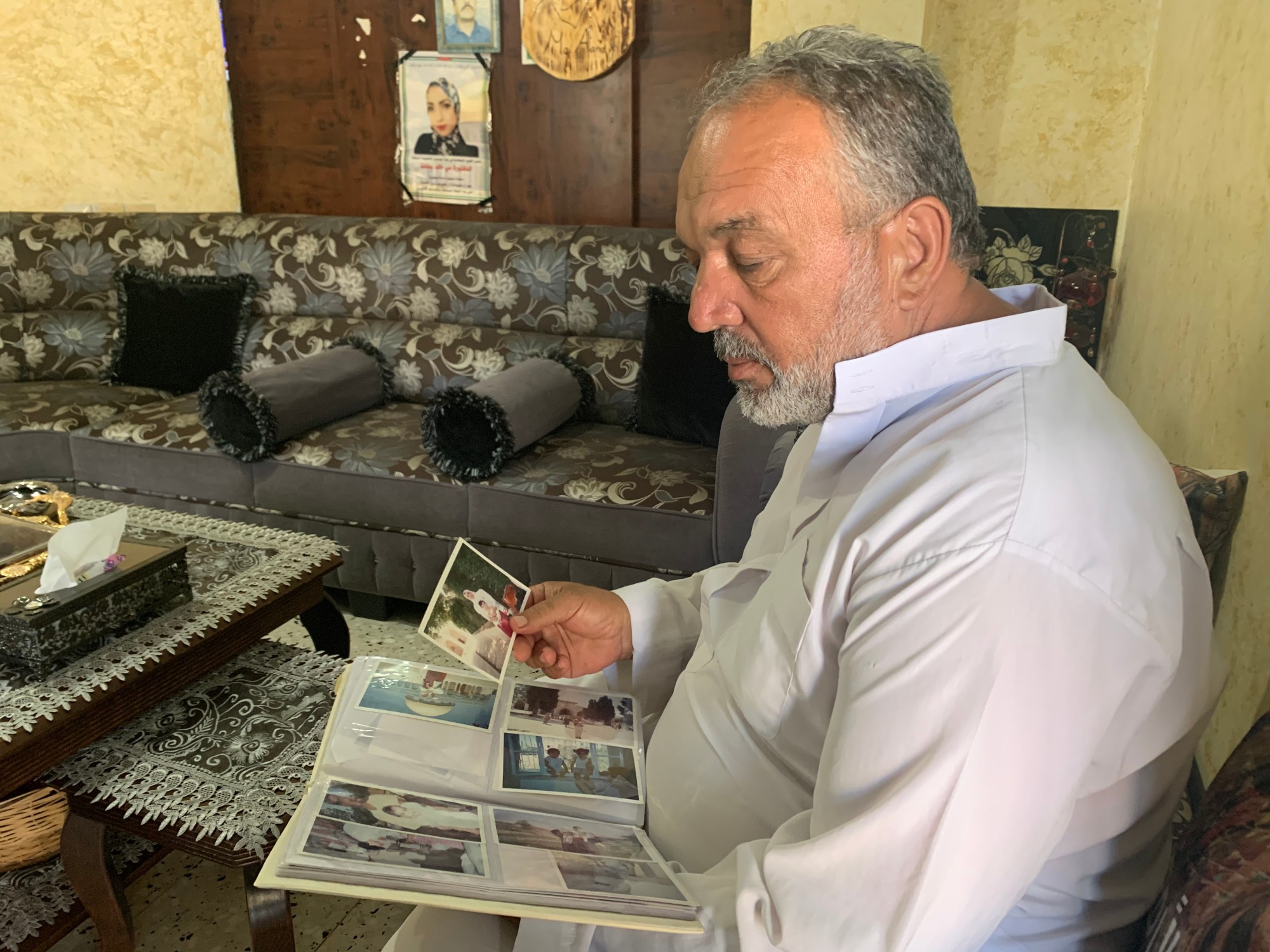 Khaled Afana looks through photographs of his daughter Mai in the family home in Abu Dis, near Jerusalem (MEE/Shatha Hammad)