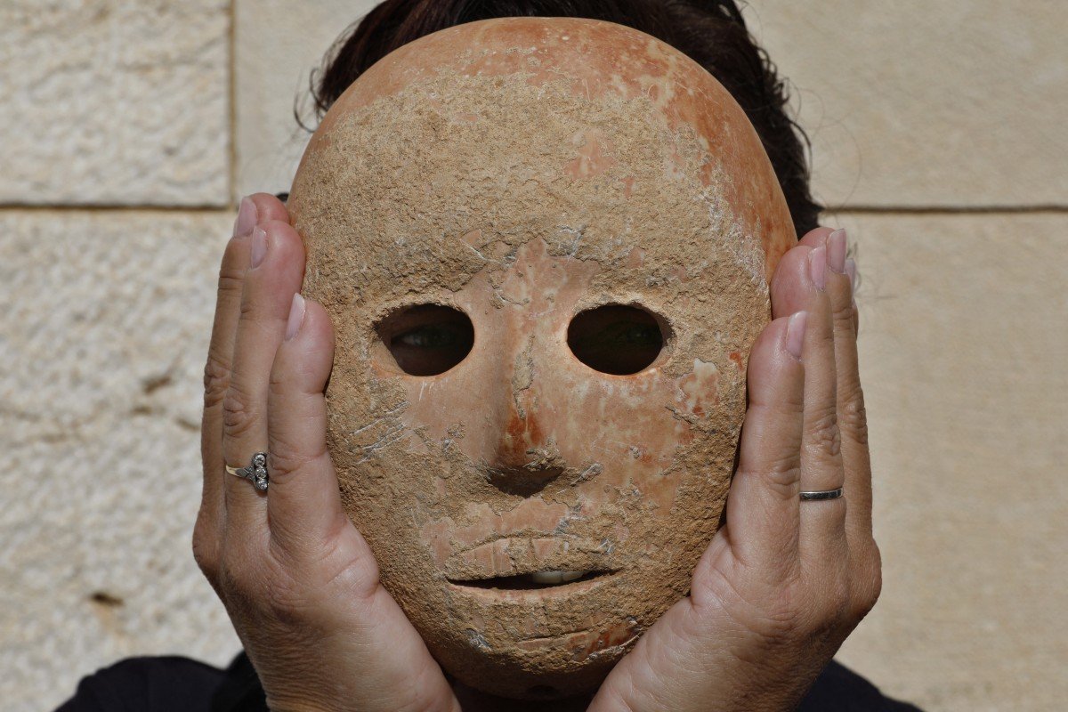 L’archéologue israélien Ronit Lupu tient un masque en pierre rare datant de la période néolithique, trouvé dans la région de Pnei Hever, au sud du mont Hébron (AFP)