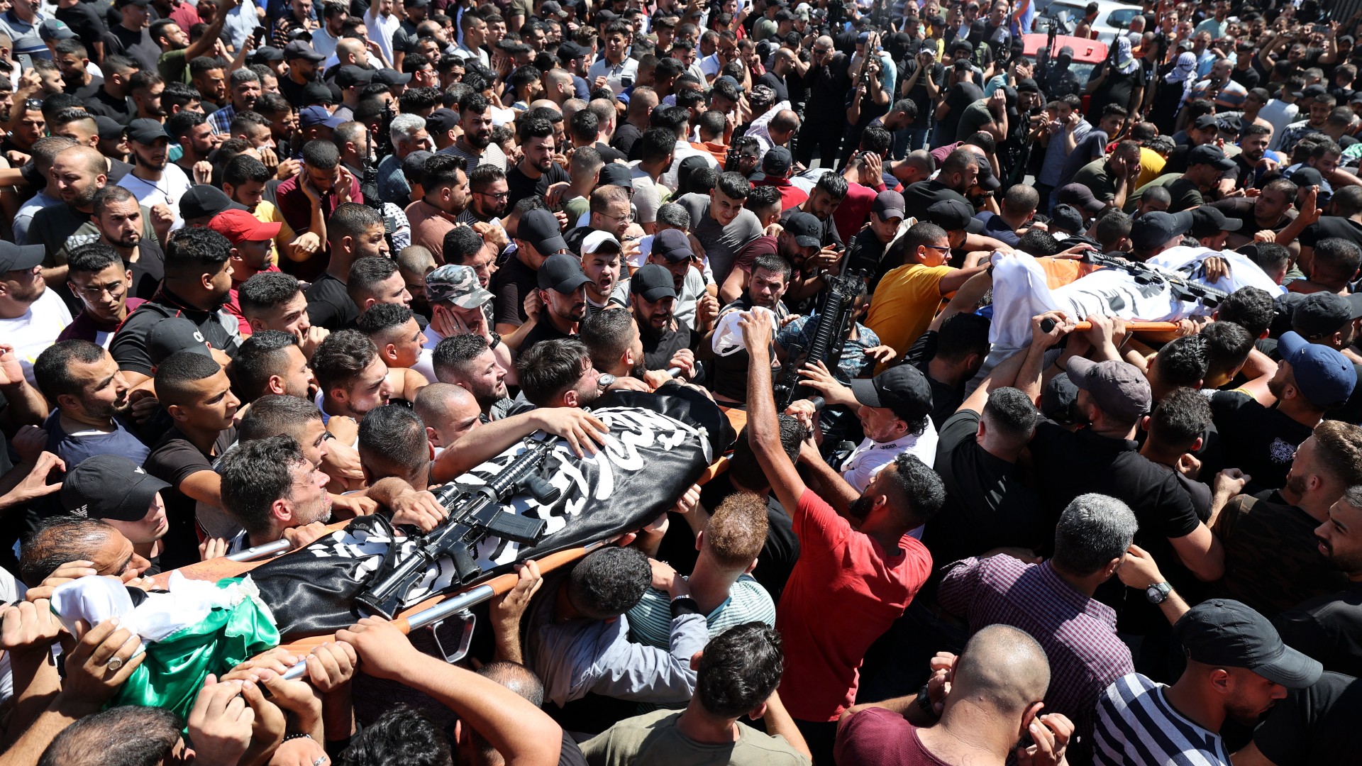 Mourners carry the body of one of two Palestinians killed earlier in confrontations with Israeli troops in the old quarter of the West Bank city of Nablus, during their funeral procession in the same city, on July 24, 2022