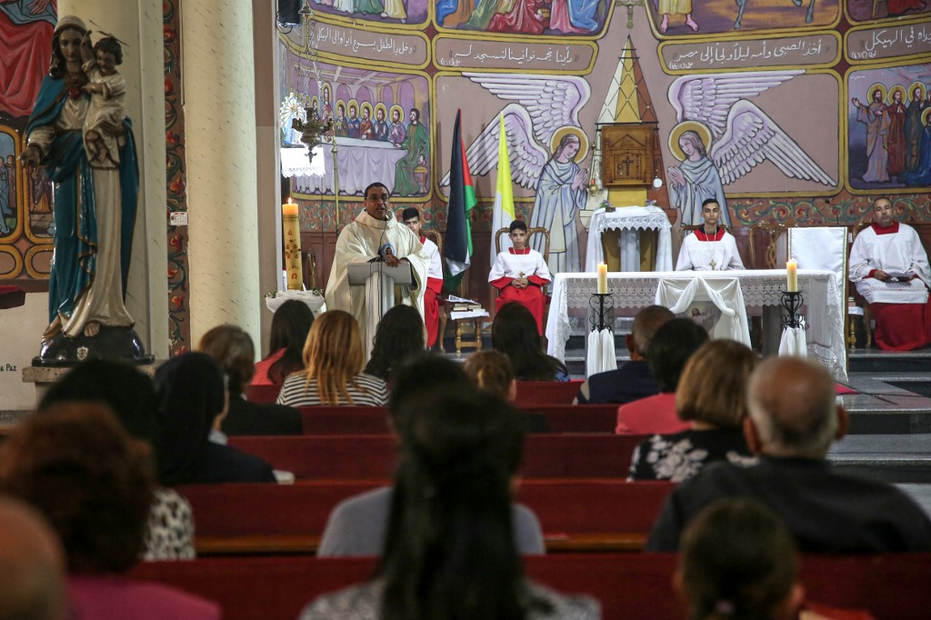 Palestinian Christian worshippers pray as a priest leads the Easter Sunday Mass at the Catholic Holy Family Church in Gaza City, 31 March 2024 (AFP)