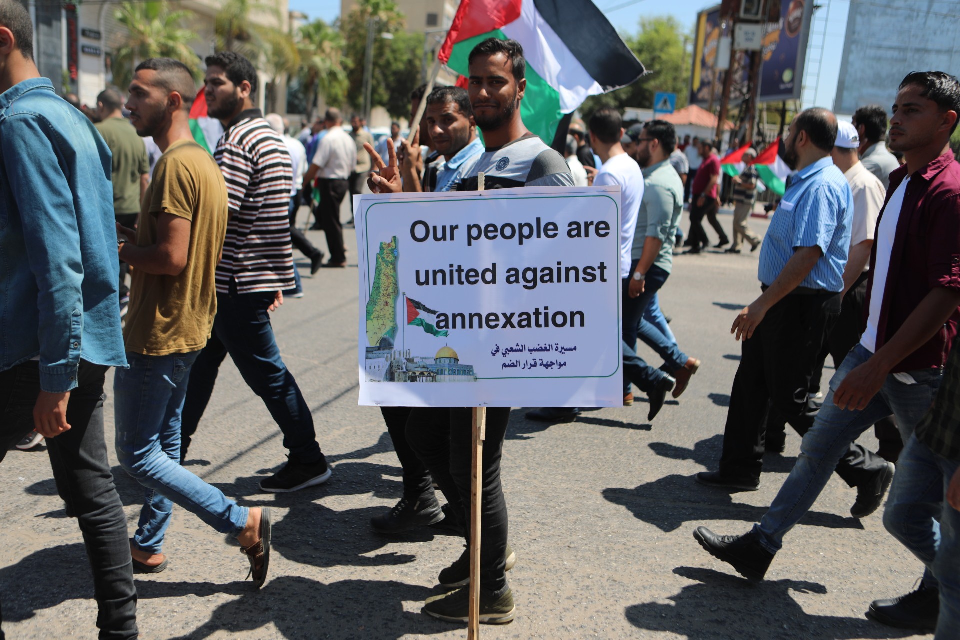 A Palestinian carrying a placard during a protest against Israeli annexation in the Gaza City on 1 July 2020 (MEE/Mohammed Hajjar)