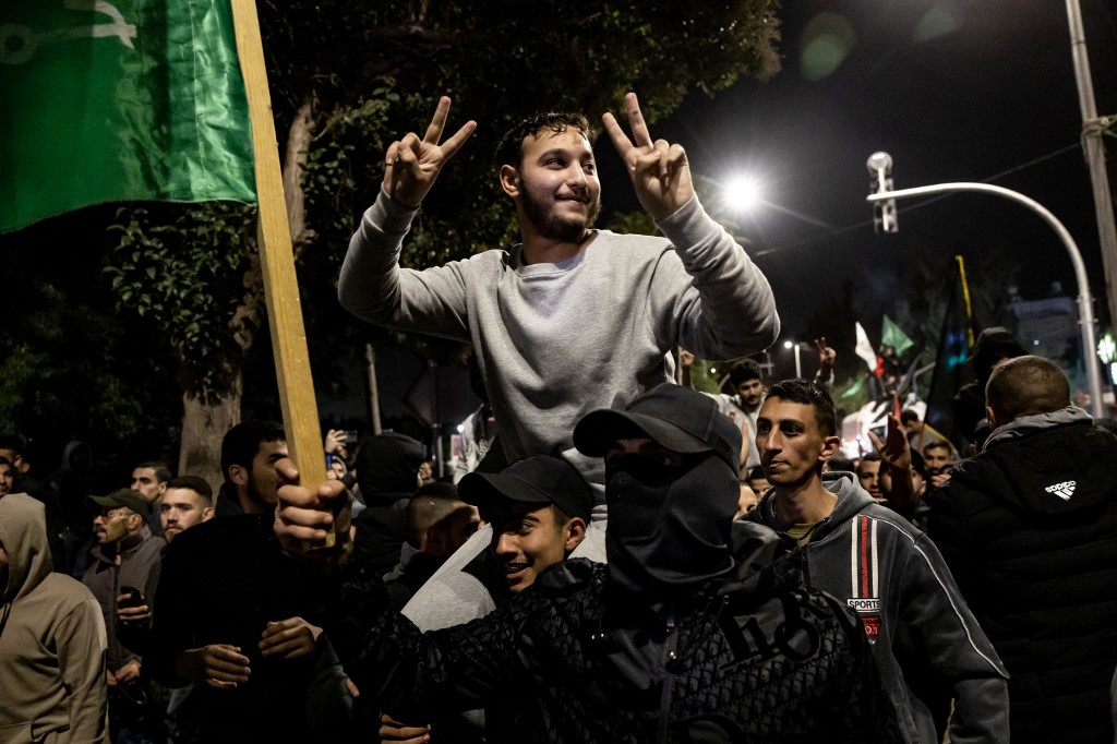 Palestinian prisoners (wearing grey jumpers) cheer among supporters and relatives after being released from Israeli jails, in Ramallah in the occupied West Bank, 26 November 2023 (AFP)