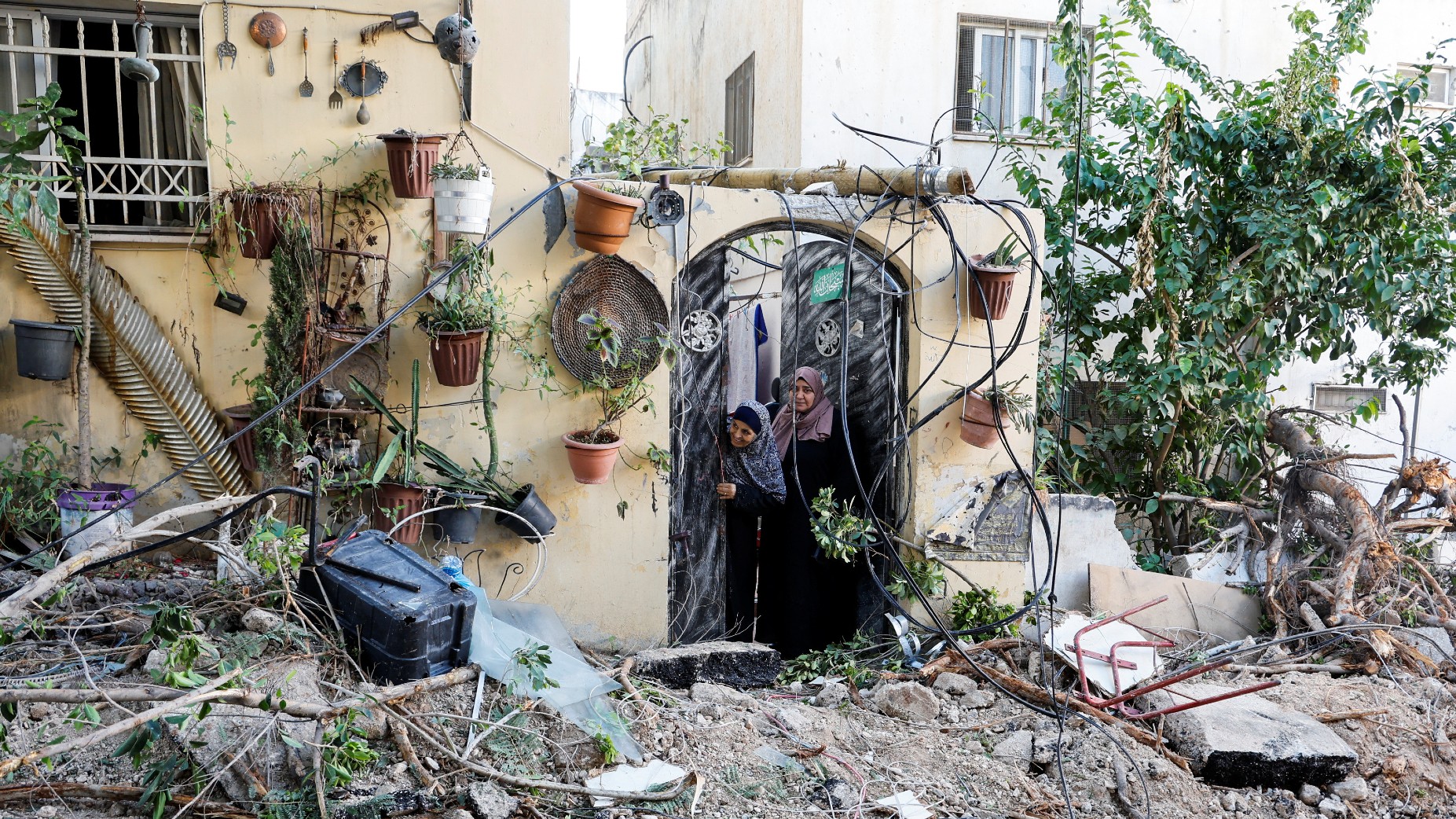 Des Palestiniennes regardent par l’embrasure d’une porte après un raid des forces d’occupation israéliennes à Jénine, en Cisjordanie occupée, le 29 novembre 2023 (Reuters)