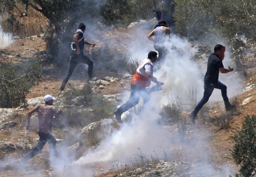 Des Palestiniens se dispersent après des tirs de gaz lacrymogènes par les forces israéliennes pendant une manifestation contre l’avant-poste de Givat Eviatar dans le village de Beita, au nord de la Cisjordanie occupée, le 13 août 2021 (AFP)