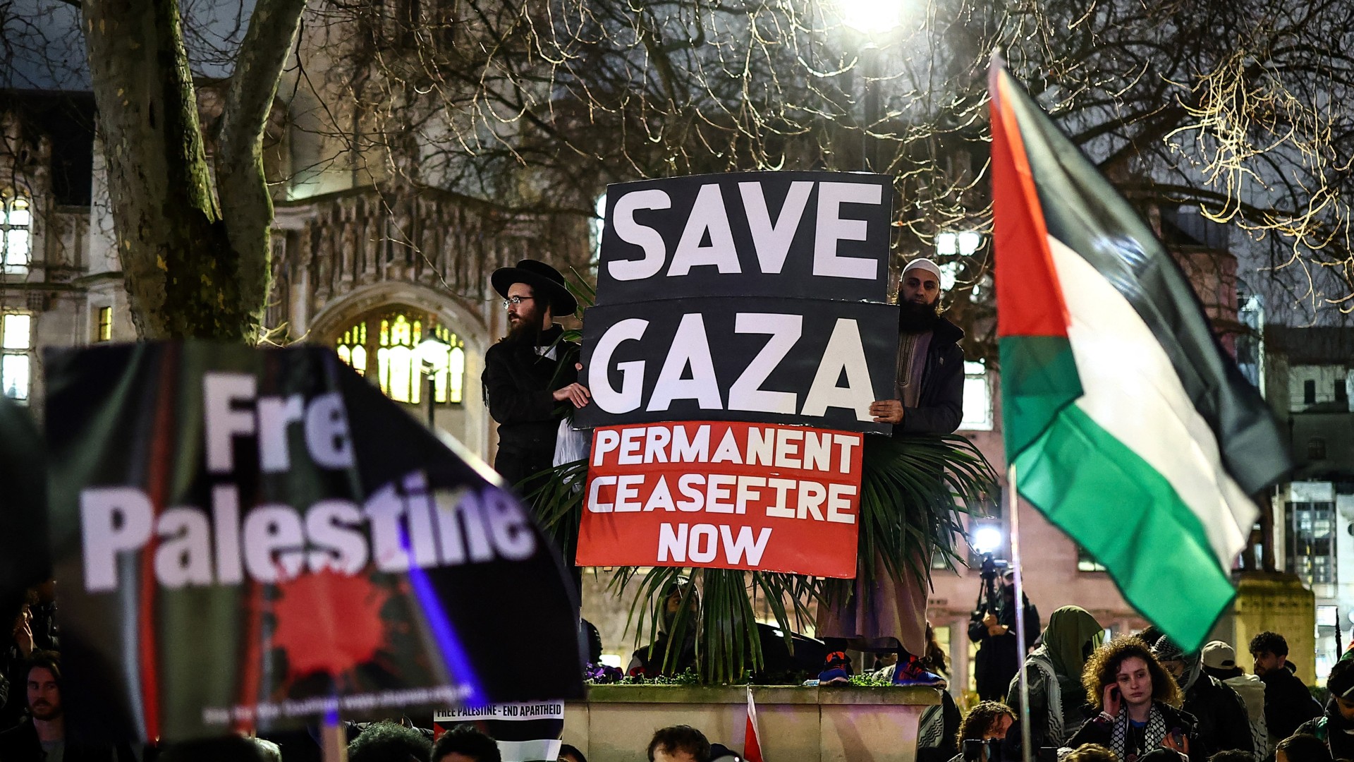 Pro-Palestinian demonstrators wave Palestinian flags and hold placards as they protest in Parliament Square in London on February 21, 2024,