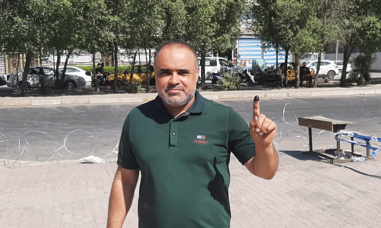 Voter in Baghdad's Sadr City displays inked finger as proof of voting (MEE/Alex MacDonald)