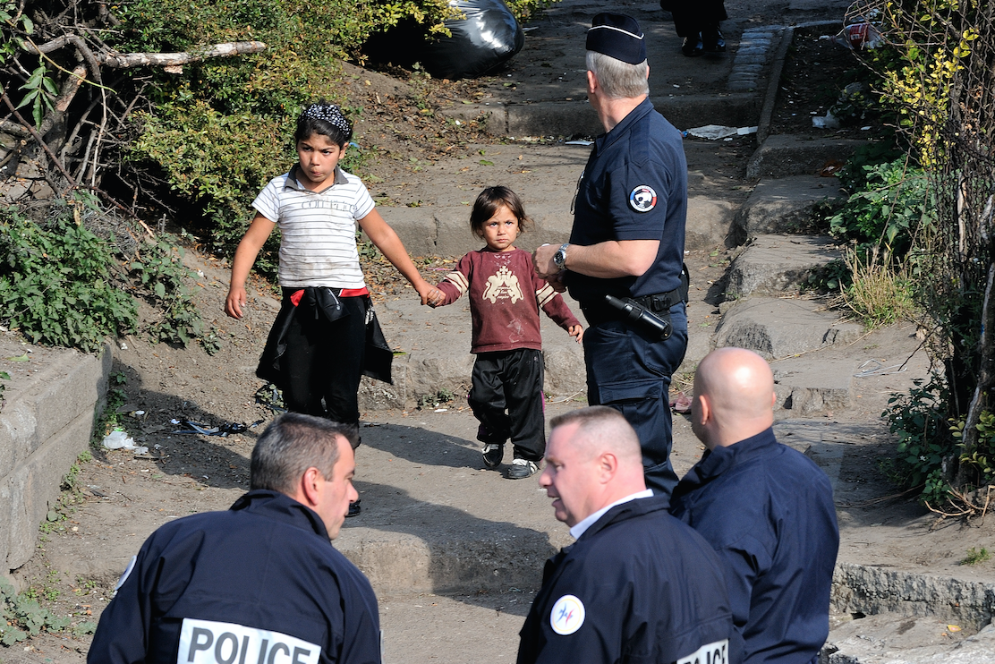 Des enfants marchent à côté de la police française lors d’un contrôle d’identité dans un campement de Roms, le 1er octobre 2013 à Roubaix, dans le nord de la France (AFP)