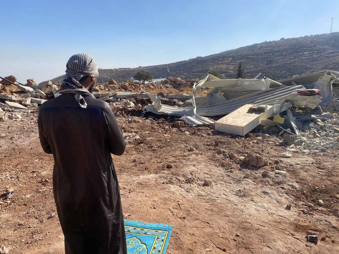 A worshipper prays at the site of the demolished mosque (MEE/Mosab Dawabsheh)