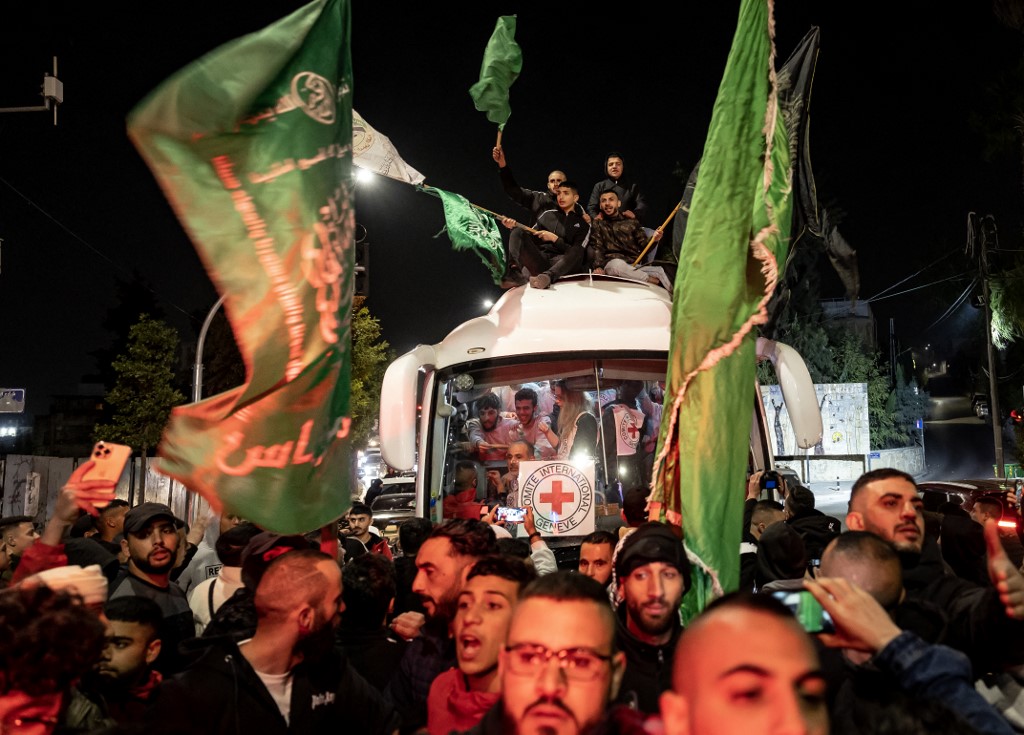 A crowd surrounds a Red Cross bus carrying Palestinian prisoners released from Israeli jails, in Ramallah in the occupied West Bank on 26 November 2023 (AFP)