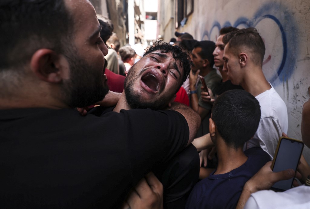 The friend of a young Palestinian killed during the night in the Jabalia refugee camp in the northern Gaza Strip, reacts during his funeral in the same camp, 7 August 2022 (AFP)