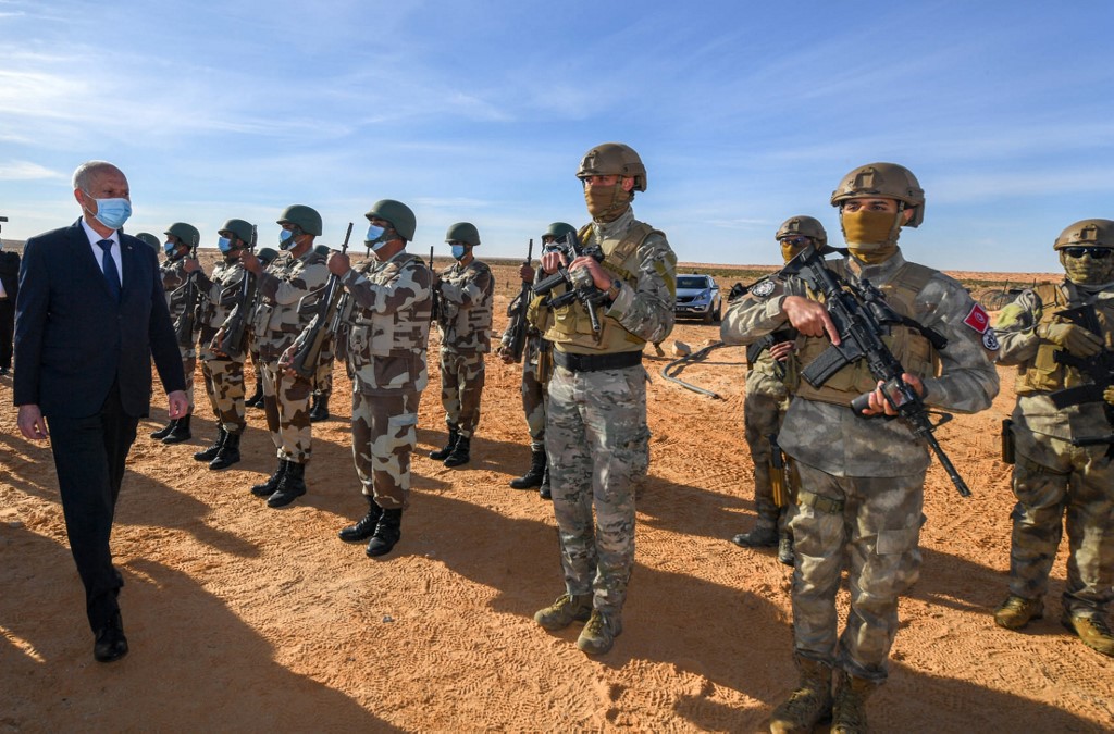 Tunisian President Kais Saied walks past troops in Ain Sekhouna, south of Tunisia, where a land dispute between tribes escalated, on 14 December 2020 (Tunisian Presidency/AFP)