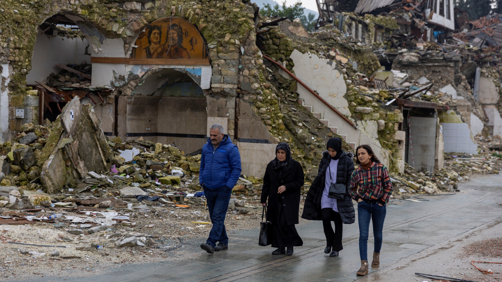 People walk past houses destroyed by last year's earthquake, in Hatay, 5 February (Reuters/Umit Bektas)