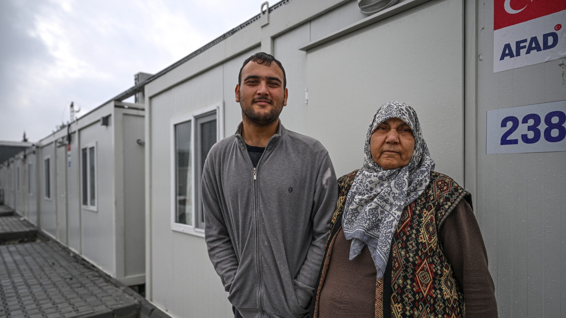 Survivors pose outside a line of housing containers in Antakya, 12 January (AFP/Ozan Kose)