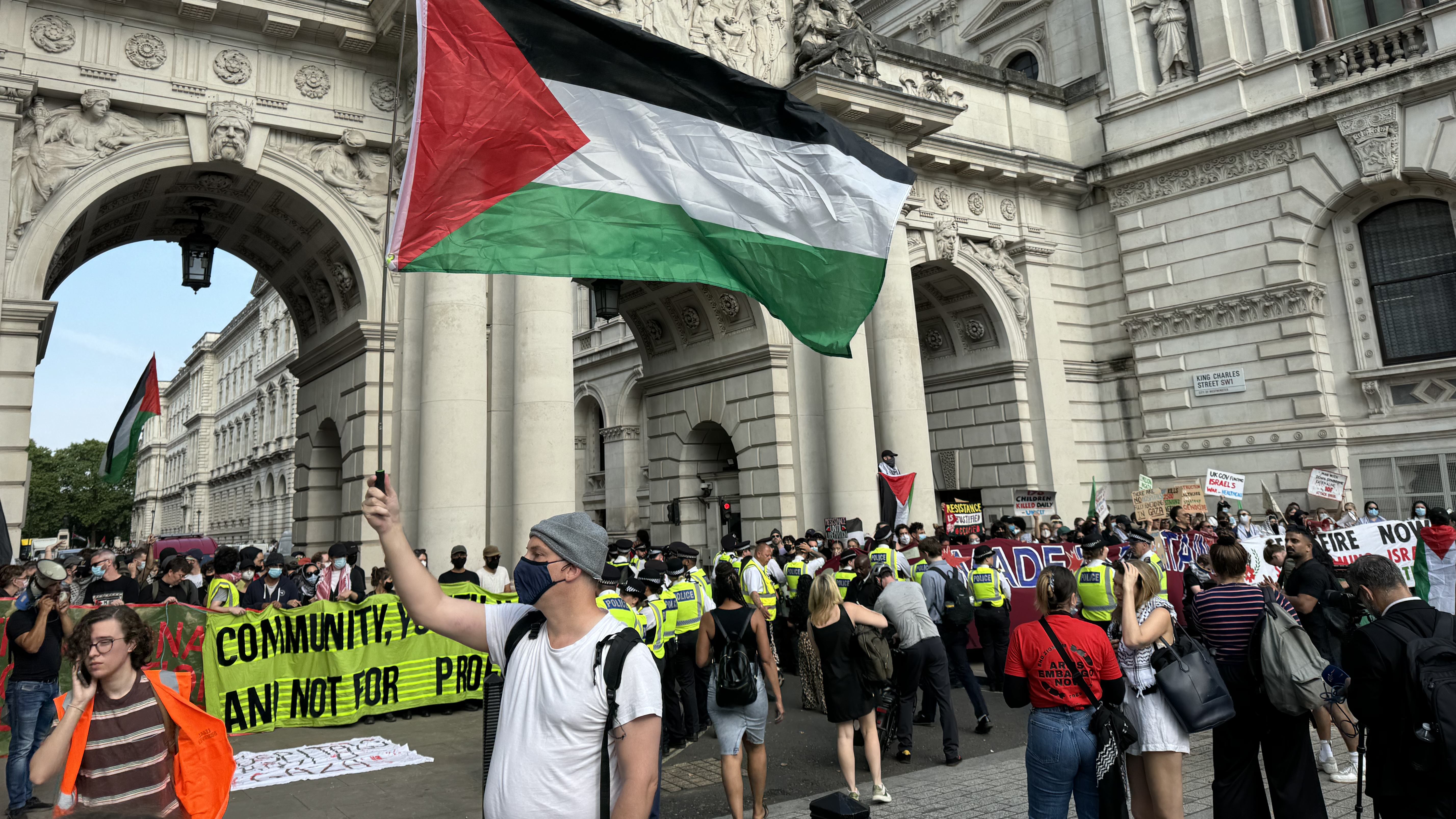 A man flies Palestinian flag in front of blockaded Foreign Office entrance in London on Wednesday (Mohammad Saleh/MEE)