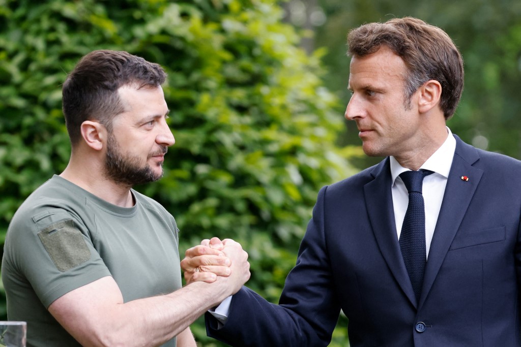 Ukrainian President Volodymyr Zelensky (L) and French President Emmanuel Macron shake hands after giving a press conference in Kyiv, on 16 June 2022 (AFP)