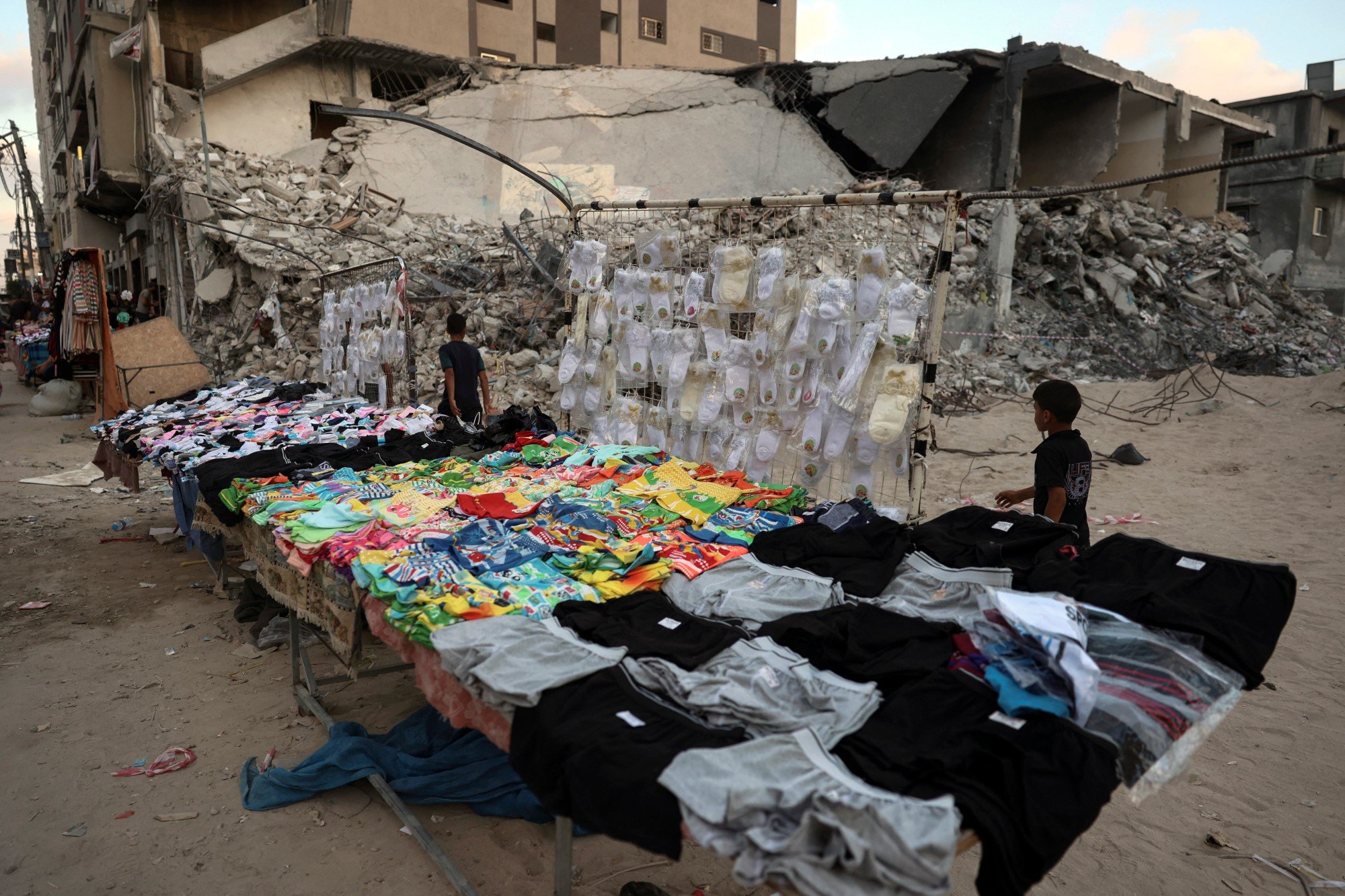 Un étal de vêtements est dressé près des décombres de la tour al-Shorouk, visée par des frappes israéliennes en mai, le 12 juillet 2021 (AFP)