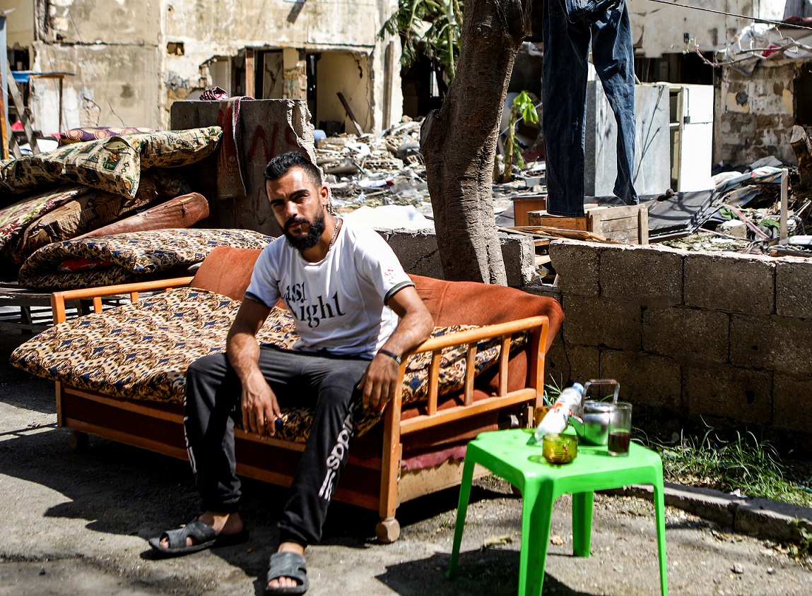 Un réfugié syrien de Hama est assis sur le canapé qu’il a réussi à récupérer des décombres de son domicile, dans le quartier de Karantina à Beyrouth, après l’explosion (AFP)