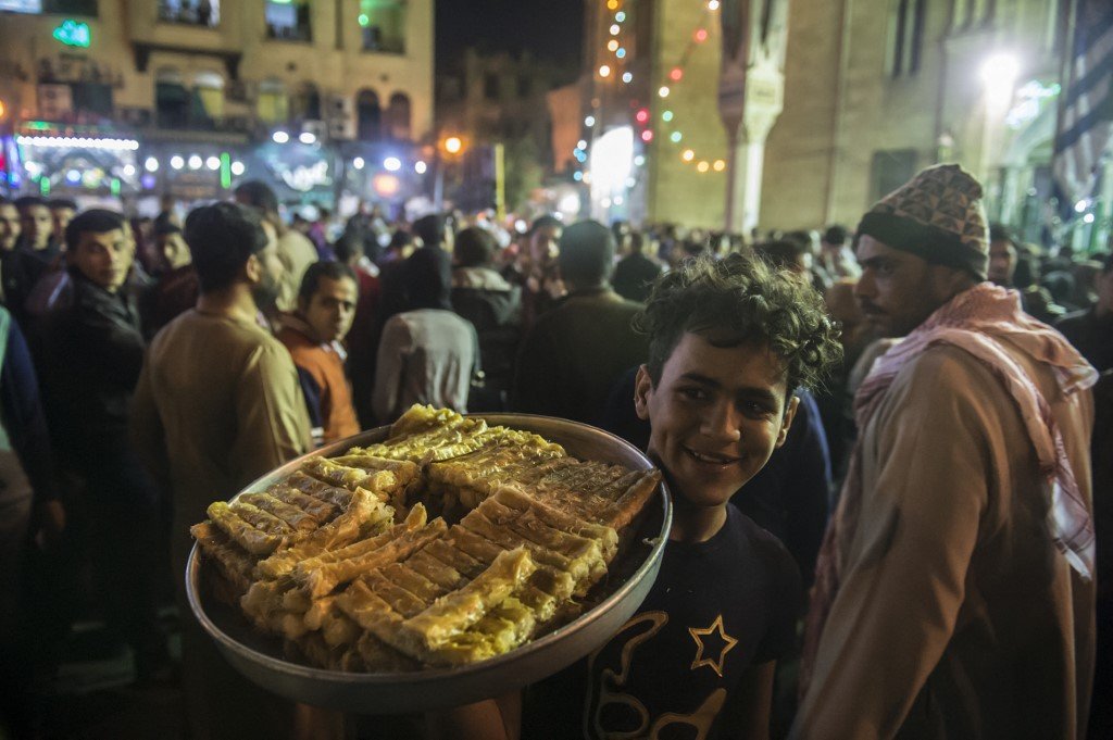 Un vendeur de rue vend des sucreries tandis que des musulmans égyptiens se rassemblent à l’extérieur de la mosquée al Hussein au Caire lors des fêtes de Mawlid (AFP)