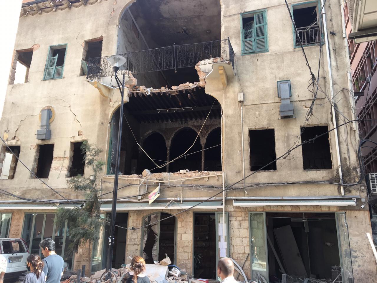 Protesters walk past a building Mar Mikhael destroyed by Tuesday's explosion (Kareem Chehayeb)